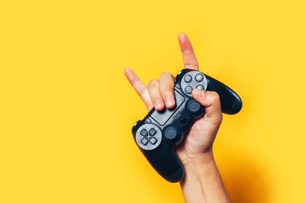  tenir à la main une manette de jeu vidéo et faire le signe des cornes 